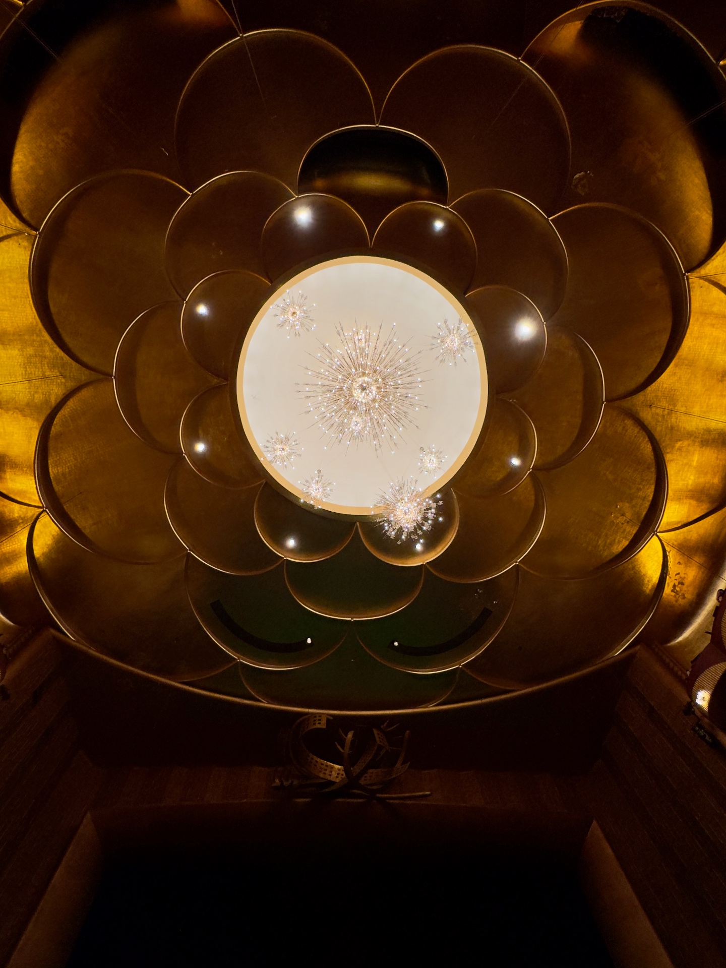 Looking straight up at the Metropolitan Opera lobby ceiling, gold leaf scalloped coffers framing the Sputnik chandelier